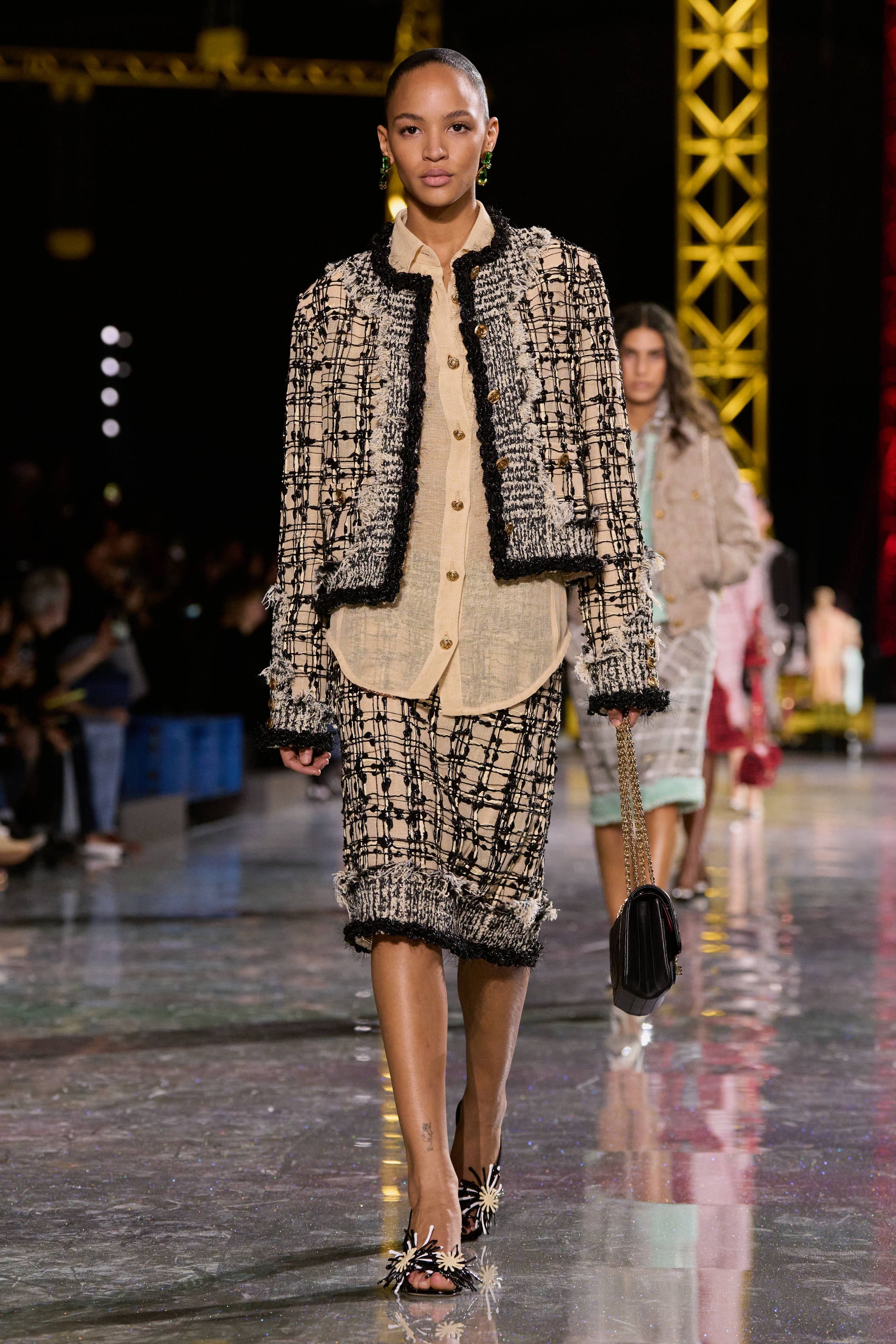 Chanel 2026秋冬在金属结构的秀场中重申品牌经典语言：斜纹软呢套装、短外套、膝下裙与珍珠配饰贯穿始终，柔粉、米色、黑白格纹与酒红色调构建出典型的巴黎优雅衣橱。本季轮廓更偏向轻松化比例，短夹克与宽松半裙形成现代化节奏，粗花呢被重新演绎为更轻盈的织物结构，同时融入羽毛、透明层纱与亮片细节，使经典香奈儿套装在年轻语境下焕发新的活力-顽石频道趋势研究